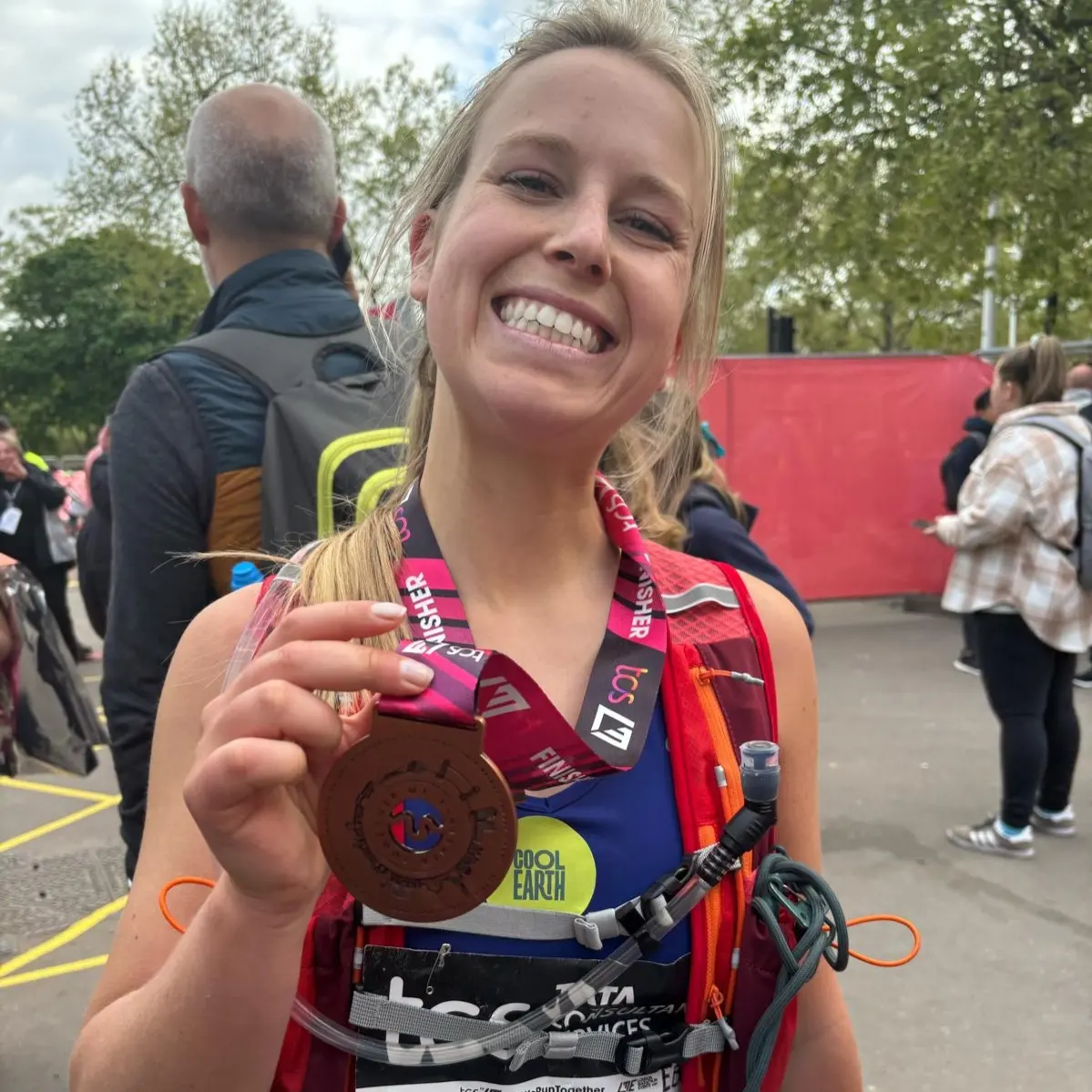 Fundraiser and London Marathon Runner smiles and proudly holds up her London Marathon medal.